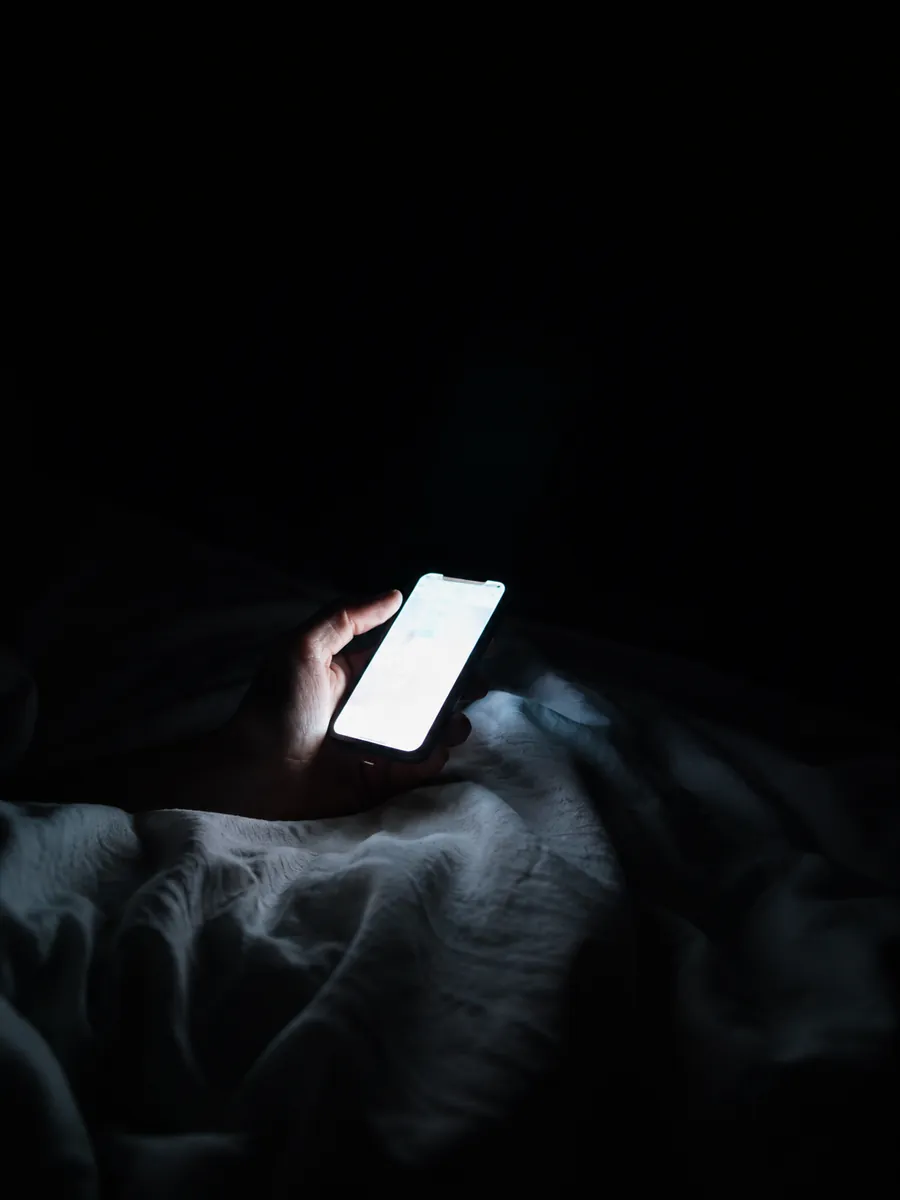Lo schermo di un telefono acceso al buio sopra un letto